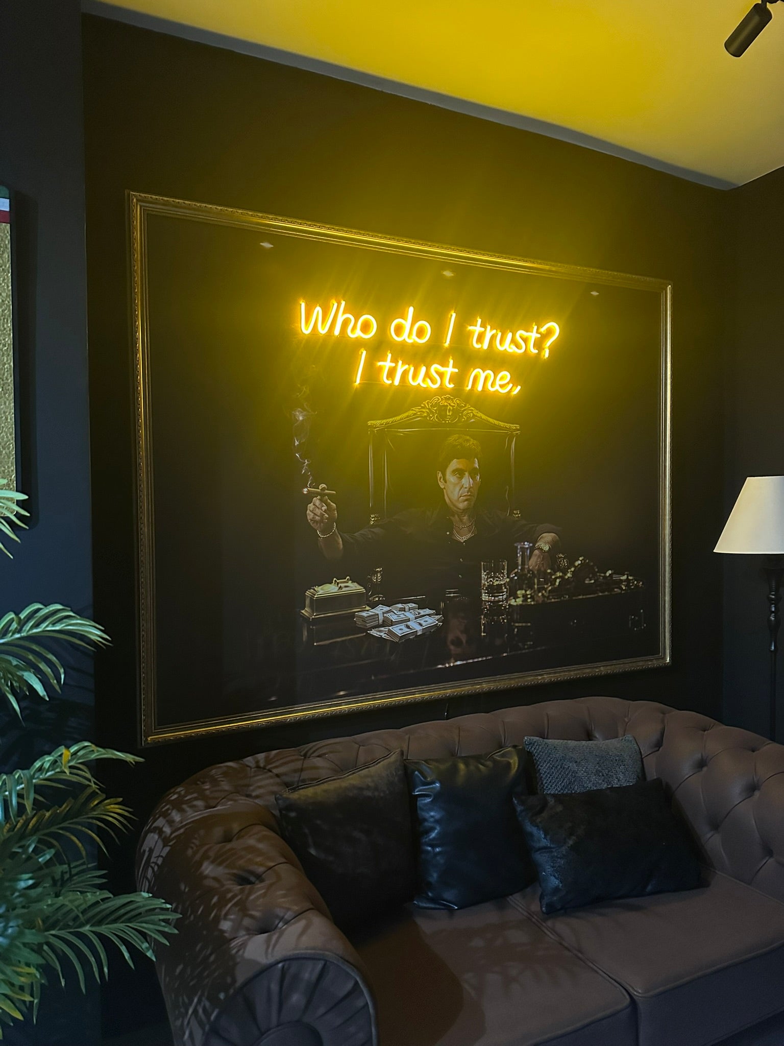 Neon sign with text 'Who do I trust? I trust me.' in a room with a couch and plant.