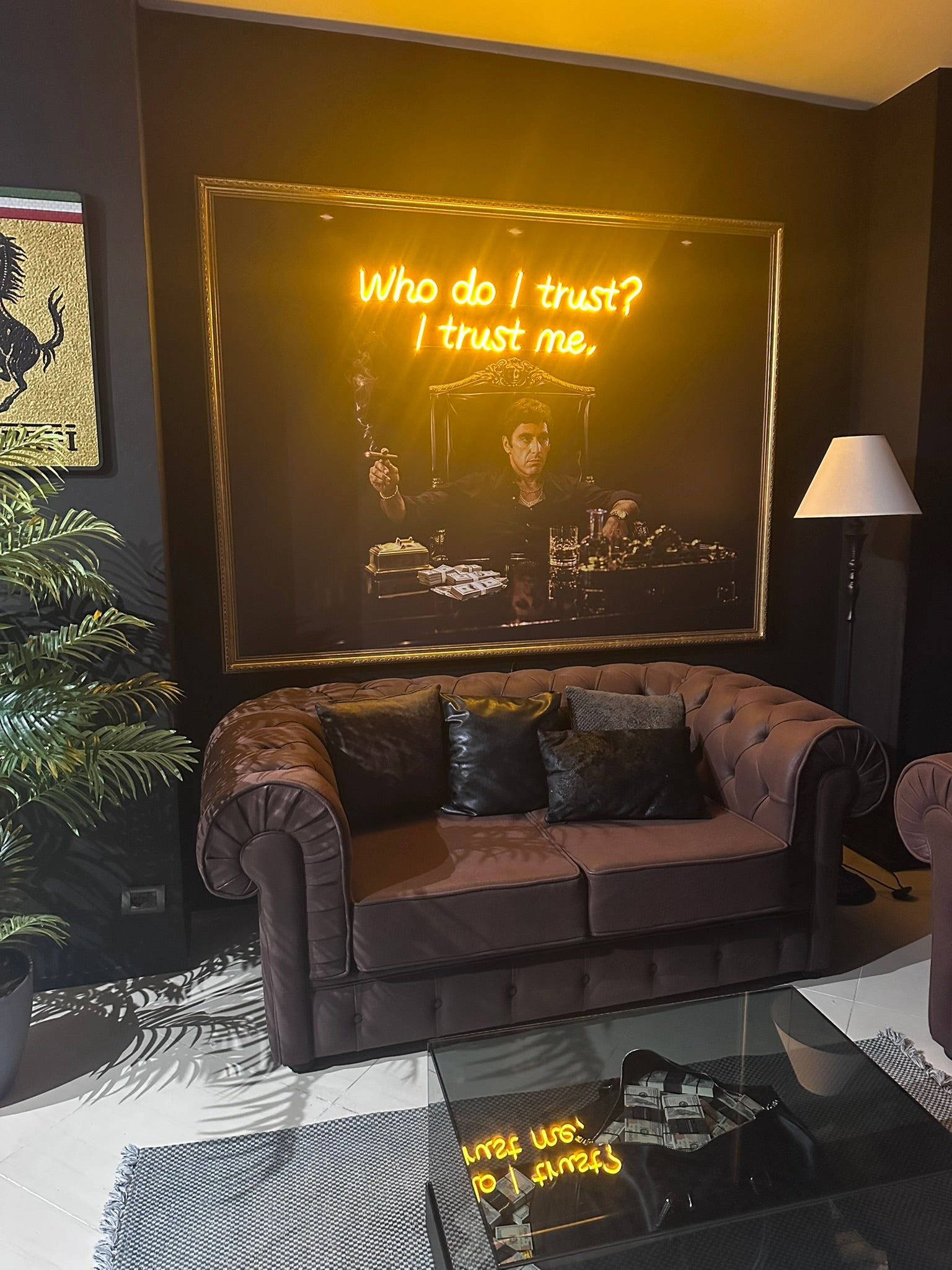 Living room with a brown sofa, glass coffee table, and framed artwork on the wall.