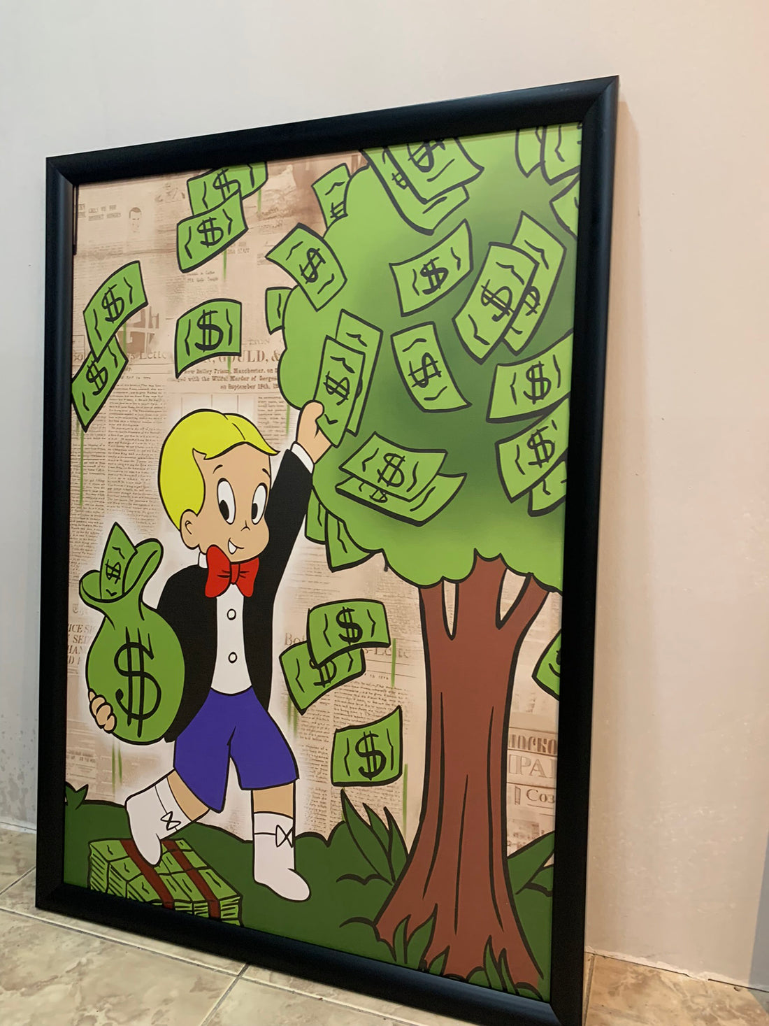 Framed cartoon artwork of a character with money tree and bag on a plain wall.